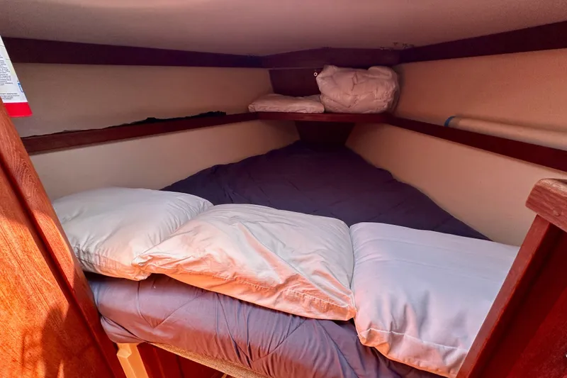 Slide: The Image of Cozy sleeping quarters in a 1989 Catalina 36 sailboat cabin with pillows and bedding. - 54