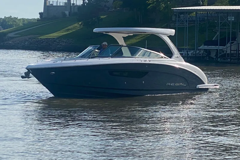 Slide: The Image of 2021 Regal 3300 Bowrider boat cruising on a calm lake near a dock. - 1