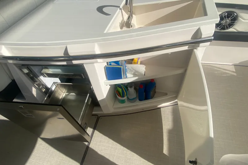 Slide: The Image of 2021 Regal 3300 Bowrider interior with open storage compartments and sink. - 14