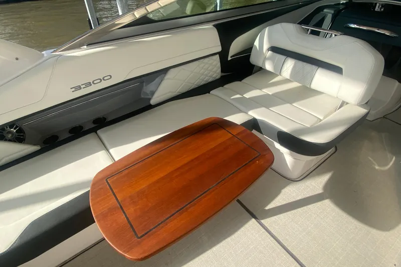 Slide: The Image of 2021 Regal 3300 Bowrider interior with white seating and wooden table. - 15