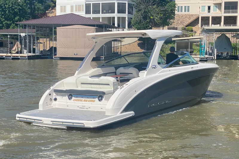 Slide: The Image of 2021 Regal 3300 Bowrider boat on calm water near marina and buildings. - 44
