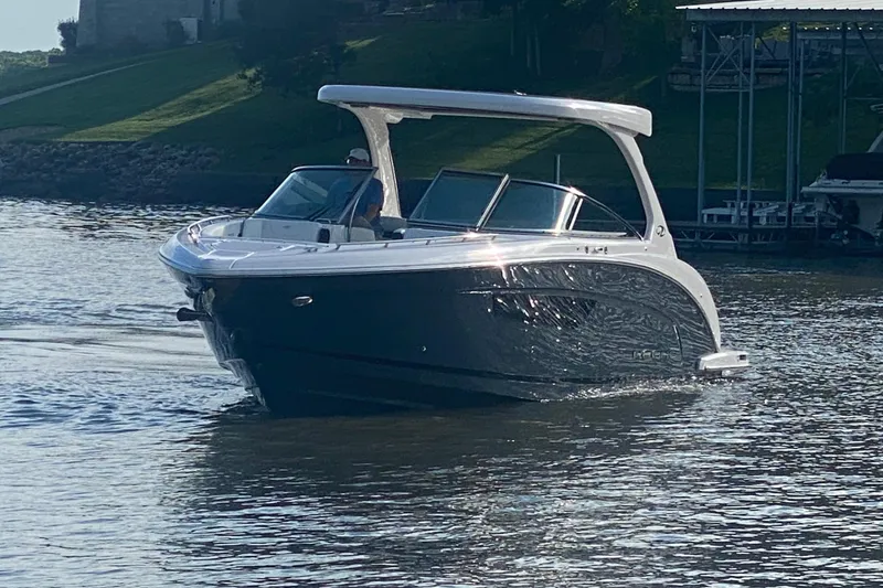 Slide: The Image of 2021 Regal 3300 Bowrider cruising on a calm lake near a dock. - 5