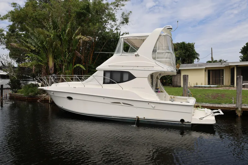 Slide: The Image of 2005 Silverton 34 Convertible yacht docked by lush greenery and a house. - 1