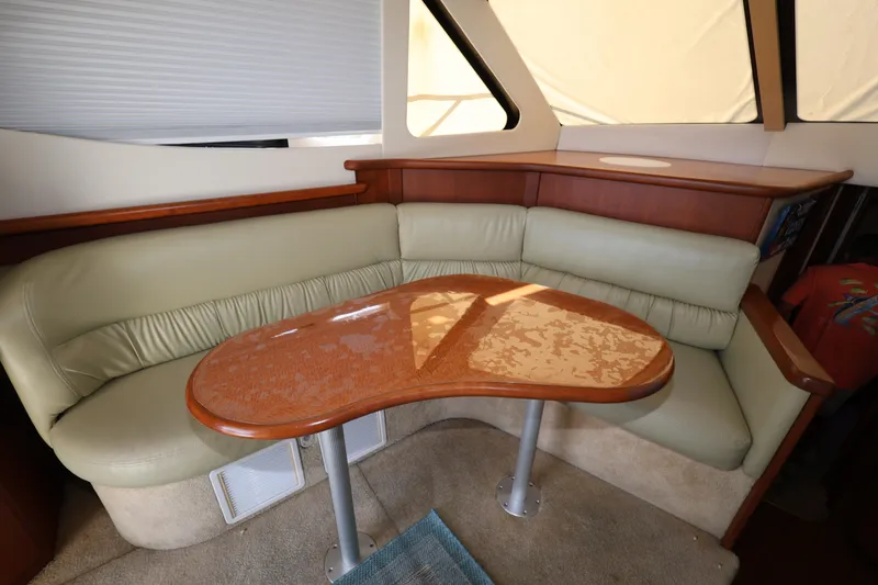 Slide: The Image of 2005 Silverton 34 Convertible yacht interior with beige leather seating and wooden table. - 10