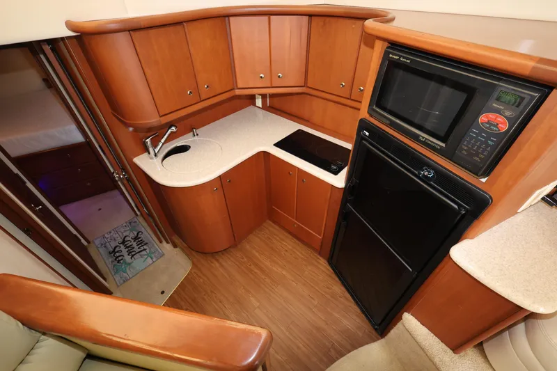 Slide: The Image of 2005 Silverton 34 Convertible yacht kitchen with wood cabinetry, compact appliances, and modern design. - 11