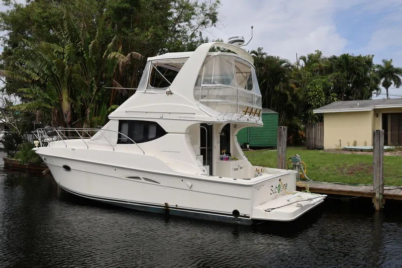 Slide: The Image of 2005 Silverton 34 Convertible yacht docked by a lush, tropical waterfront. - 2