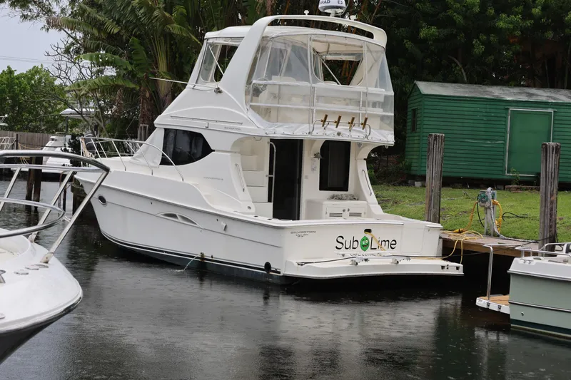 Slide: The Image of 2005 Silverton 34 Convertible yacht docked near green shed in rainy weather. - 3