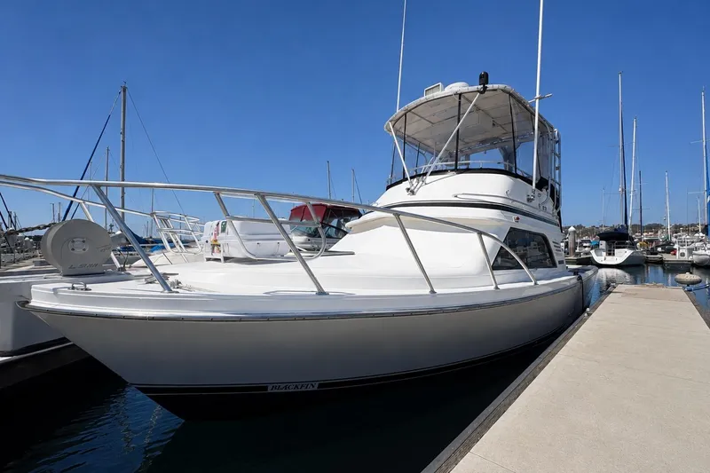 The Image of 1991 Blackfin 33 Flybridge yacht docked at marina under clear blue sky. - 0