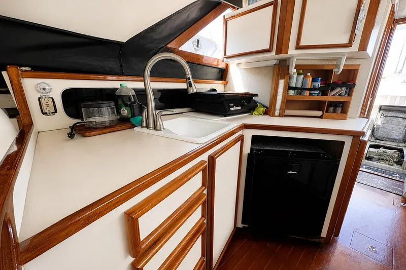 Slide: The Image of Interior of 1991 Blackfin 33 Flybridge boat kitchen with sink, cabinets, and mini fridge. - 10