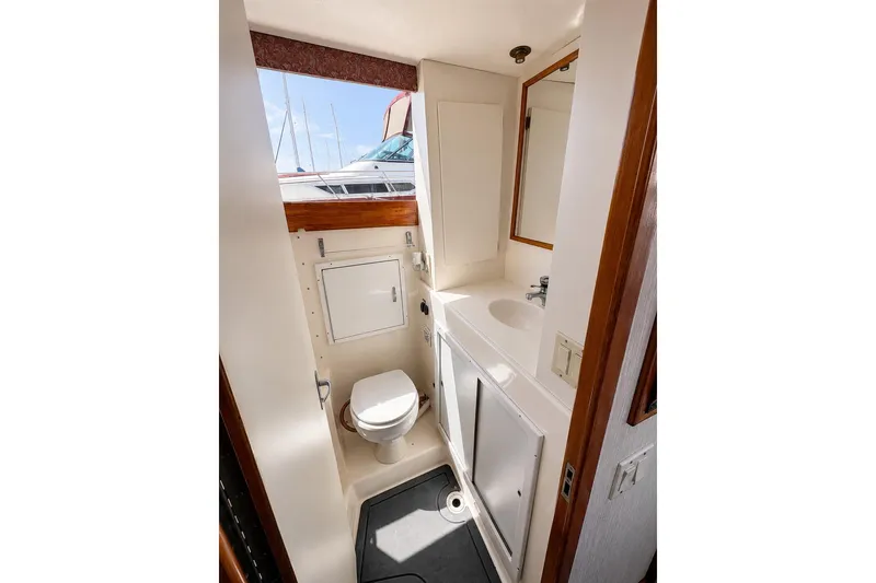 Slide: The Image of 1991 Blackfin 33 Flybridge bathroom with toilet, sink, and window view of marina. - 13