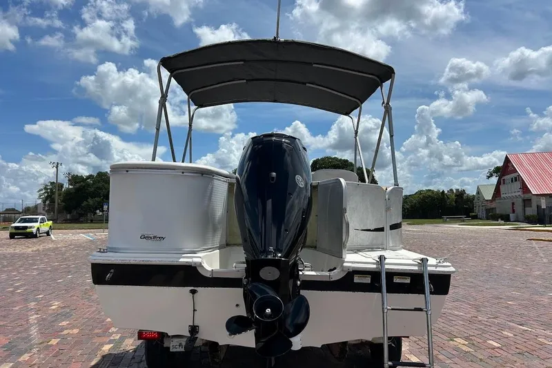 Slide: The Image of 2008 Hurricane FunDeck 226 RE boat with canopy, parked on brick pavement under a cloudy sky. - 5