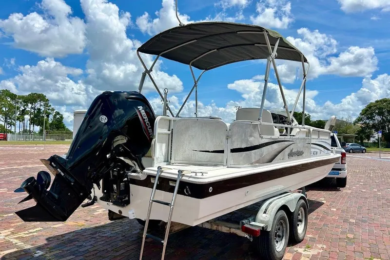 Slide: The Image of 2008 Hurricane FunDeck 226 RE boat on trailer, featuring a Mercury outboard motor under a sunny sky. - 6