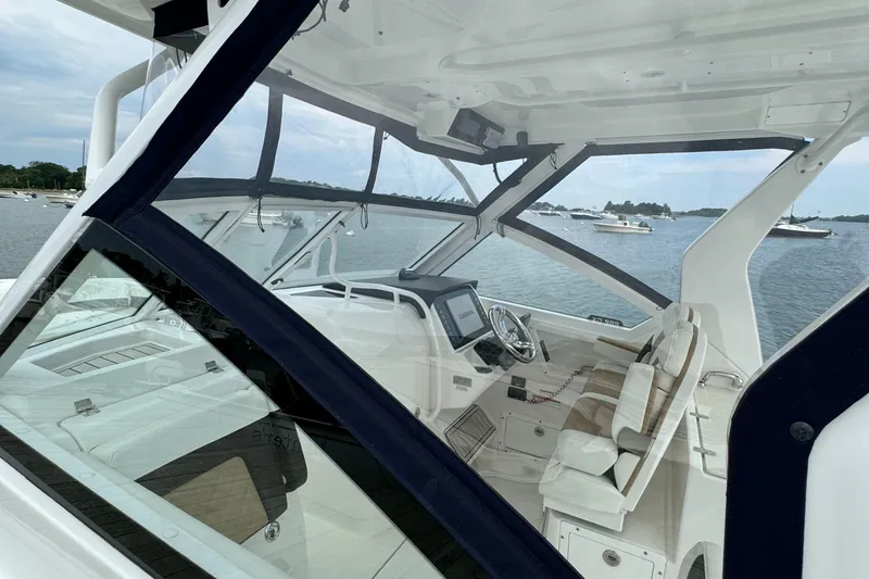 Slide: The Image of 2020 Edgewater 262 CX boat interior with modern dashboard and seating, docked on a calm lake. - 21