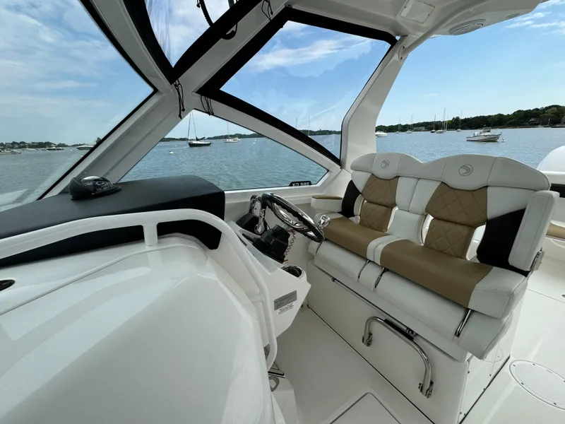 Slide: The Image of 2020 Edgewater 262 CX boat interior with helm and seating, overlooking a serene lake. - 6