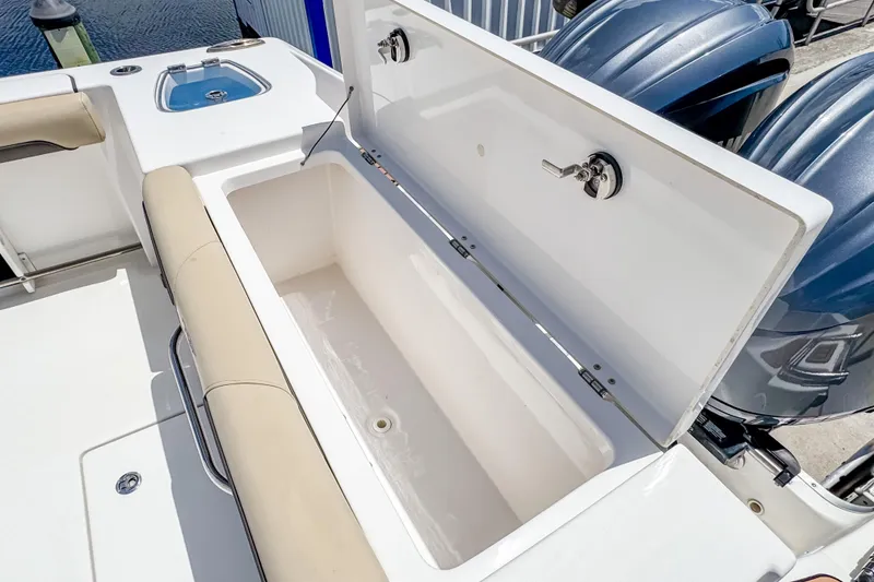 Slide: The Image of 2023 Tidewater 280 CC Adventure boat with open storage compartment and dual engines. - 9