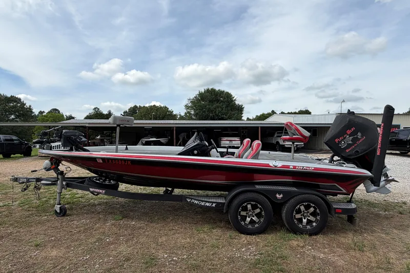 The Image of 2019 Phoenix 920 ProXP bass boat on trailer, parked outdoors under cloudy sky. - 0