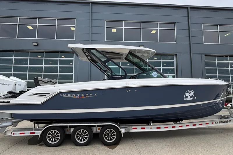 The Image of 2026 Monterey Elite 30 OB boat on trailer, parked outside a modern building. - 1