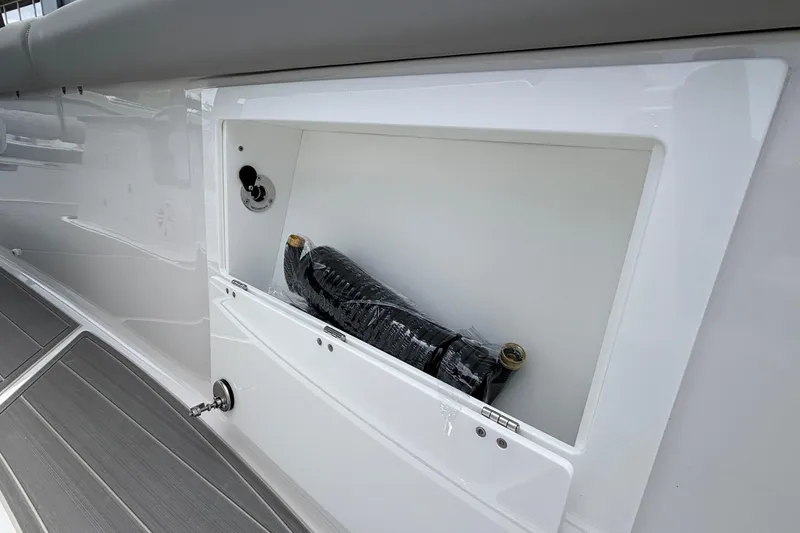 Slide: The Image of Storage compartment on a 2026 Monterey Elite 30 OB boat, featuring a coiled hose. - 62