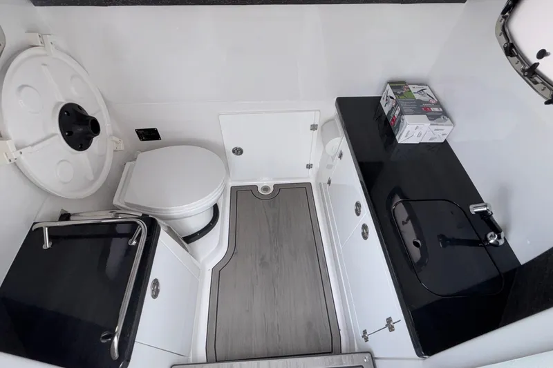 Slide: The Image of 2026 Monterey Elite 30 OB boat bathroom with toilet, sink, and storage cabinets. - 67