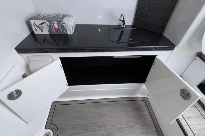 Slide: The Image of 2026 Monterey Elite 30 OB boat interior with open cabinets and sleek countertop. - 73