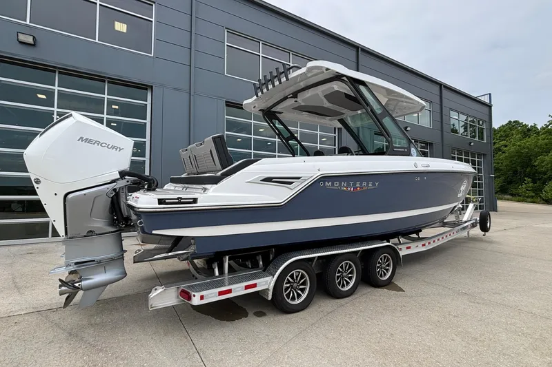 Slide: The Image of 2026 Monterey Elite 30 OB boat on trailer, parked outside modern building. - 8