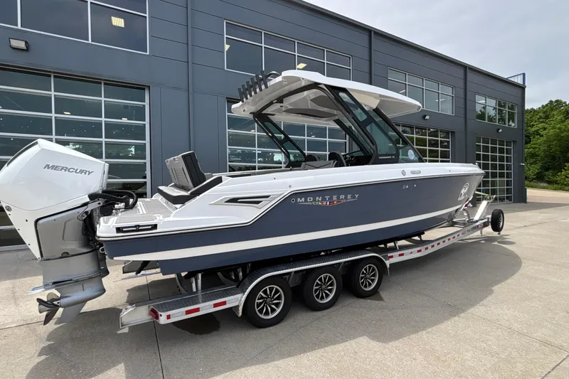 Slide: The Image of 2026 Monterey Elite 30 OB boat on trailer, parked outside modern building. - 92