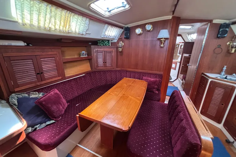 Slide: The Image of Interior of a 1990 Catalina 42 sailboat with cozy dining area and wooden furnishings. - 20