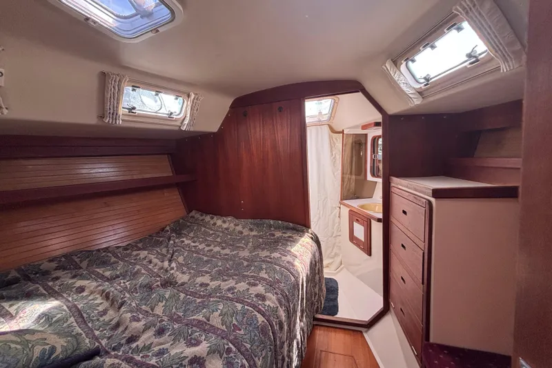 Slide: The Image of Cozy cabin interior of a 1990 Catalina 42 sailboat with wood paneling and bedding. - 38