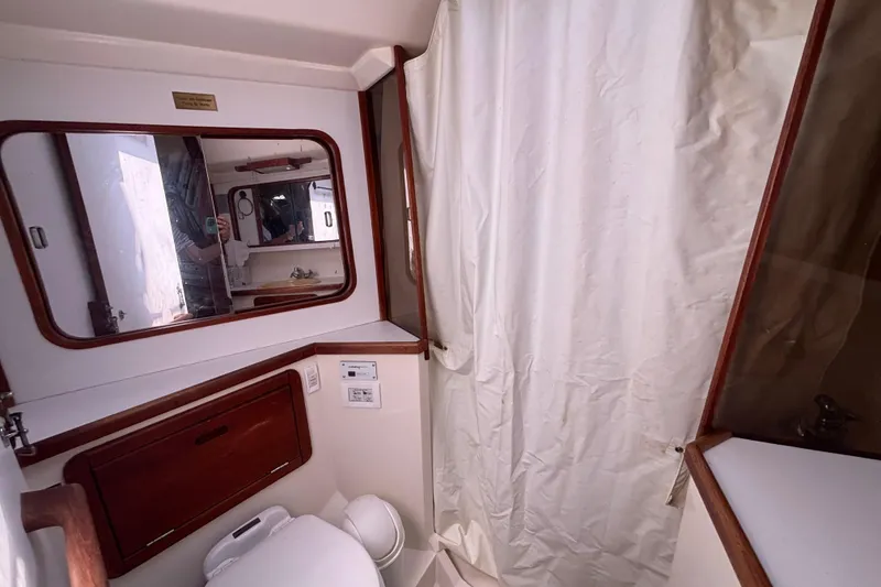 Slide: The Image of Bathroom interior of a 1990 Catalina 42 sailboat, featuring a mirror and shower curtain. - 41