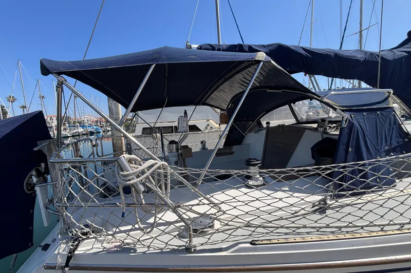 Slide: The Image of 1990 Catalina 42 sailboat with blue canopy docked at marina under clear sky. - 5