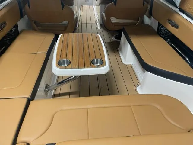 Slide: The Image of 2023 Chaparral 307 SSX boat interior with tan leather seating and wooden table. - 16