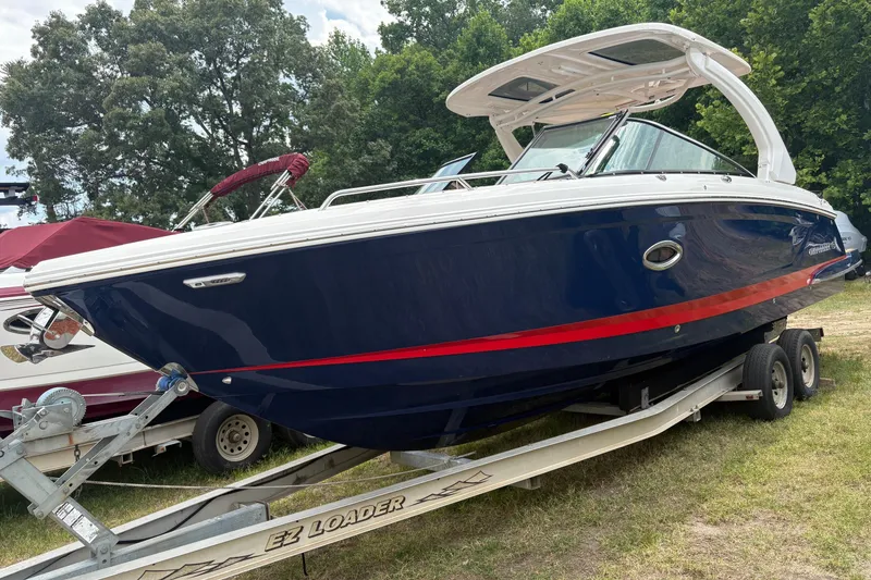 Slide: The Image of 2023 Chaparral 307 SSX boat on trailer, blue hull with red stripe, parked outdoors. - 19