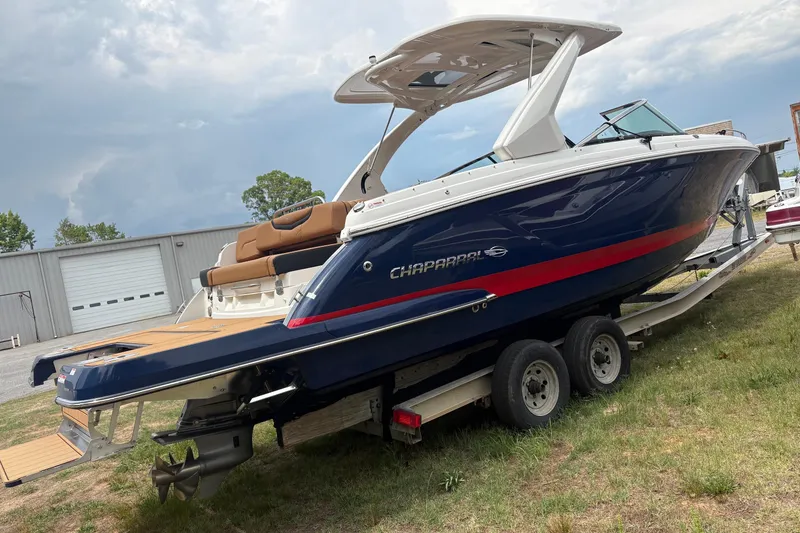 Slide: The Image of 2023 Chaparral 307 SSX boat on trailer, blue with red stripe, parked outdoors. - 21