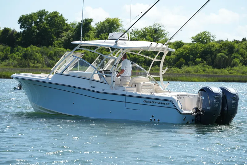 Slide: The Image of 2022 Grady-White Freedom 285 boat cruising on a sunny day with lush greenery background. - 1