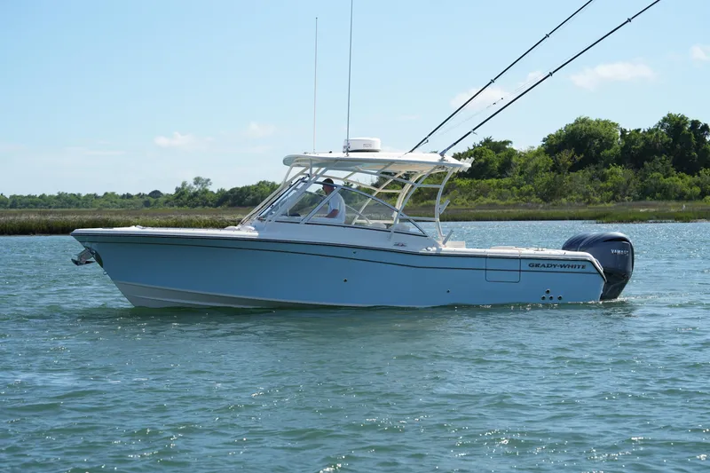 Slide: The Image of 2022 Grady-White Freedom 285 boat cruising on a sunny day, with lush greenery in the background. - 10
