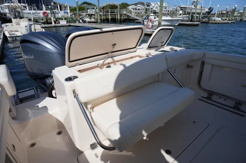 Slide: The Image of 2022 Grady-White Freedom 285 boat interior with seating and storage at a marina. - 13