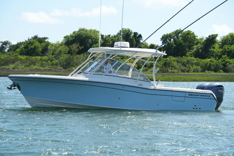 Slide: The Image of 2022 Grady-White Freedom 285 boat cruising on a sunny day near lush greenery. - 2