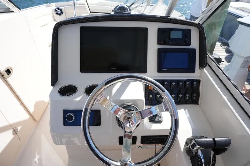 Slide: The Image of 2022 Grady-White Freedom 285 boat dashboard with steering wheel and electronic controls. - 22