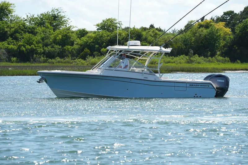 Slide: The Image of 2022 Grady-White Freedom 285 boat cruising on a sunny day near lush greenery. - 7