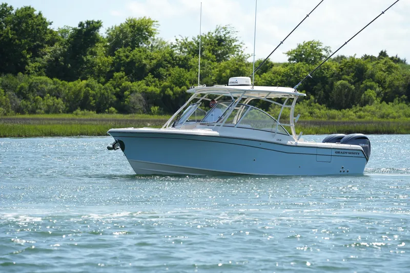 Slide: The Image of 2022 Grady-White Freedom 285 boat cruising on a scenic waterway with lush greenery. - 8
