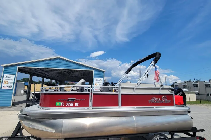 The Image of 2026 Sun Tracker Bass Buggy 16 XL Select pontoon boat at dealership under blue sky. - 1