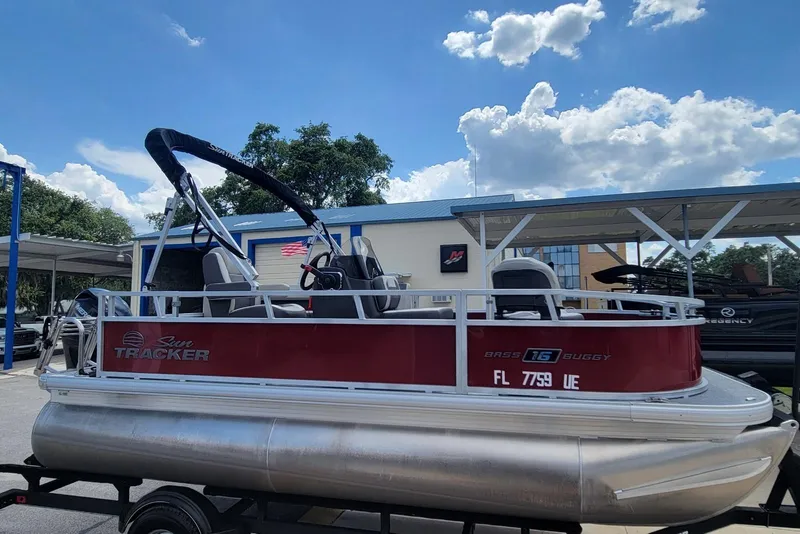Slide: The Image of 2026 Sun Tracker Bass Buggy 16 XL Select pontoon boat on trailer under blue sky. - 3