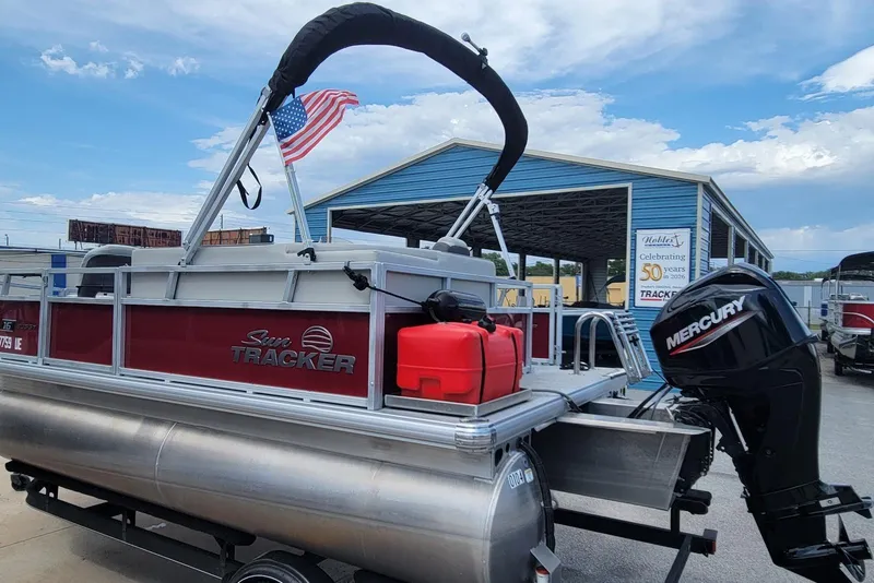 Slide: The Image of 2026 Sun Tracker Bass Buggy 16 XL Select pontoon boat with Mercury engine and American flag. - 6