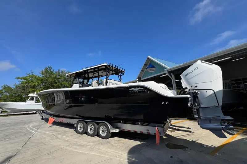 Slide: The Image of 2022 Invincible 46 Catamaran with Mercury engines on a trailer under clear blue sky. - 12