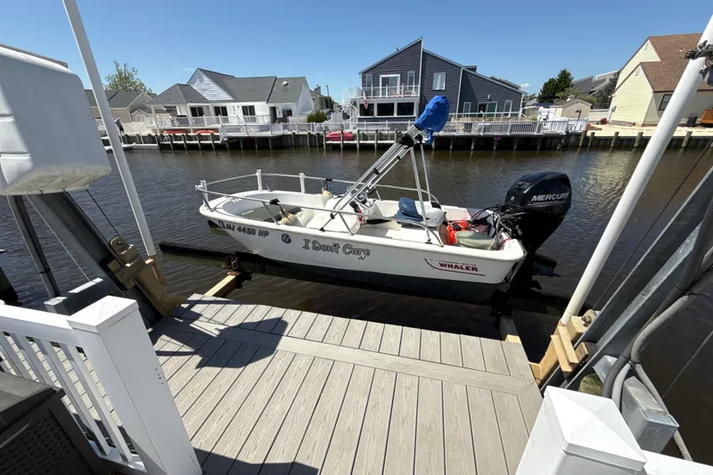 The Image of 2017 Boston Whaler 110 Sport boat docked by waterfront homes. - 0