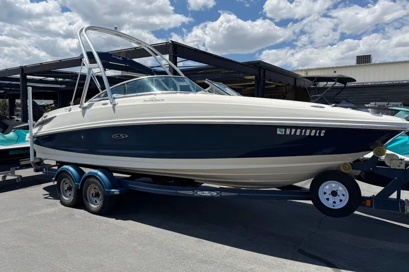 The Image of 2010 Sea Ray 230 Sundeck boat on trailer under a partly cloudy sky. - 0