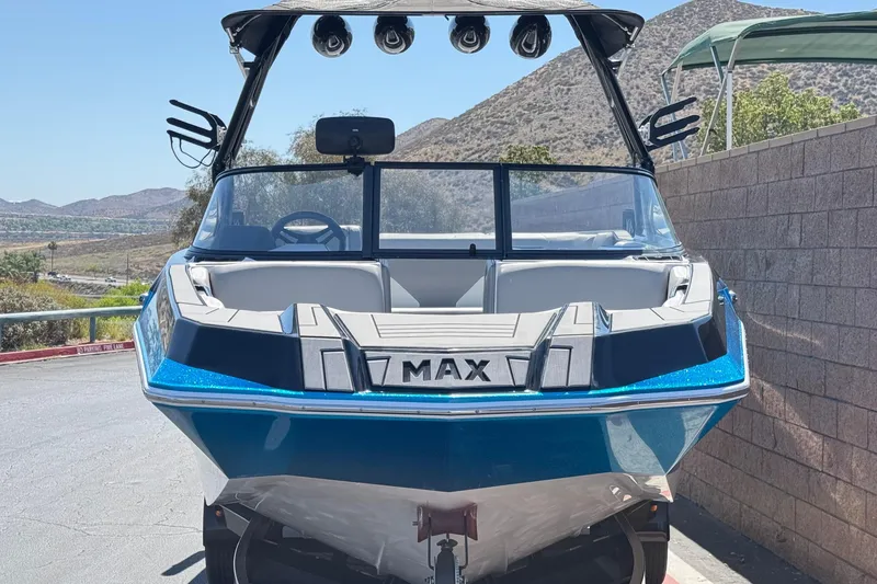 Slide: The Image of 2019 Moomba Max boat with blue exterior, parked outdoors near a stone wall. - 2