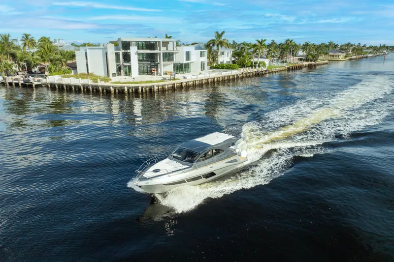 Slide: The Image of 2025 Valiatt 410HT yacht cruising near modern waterfront homes. - 1