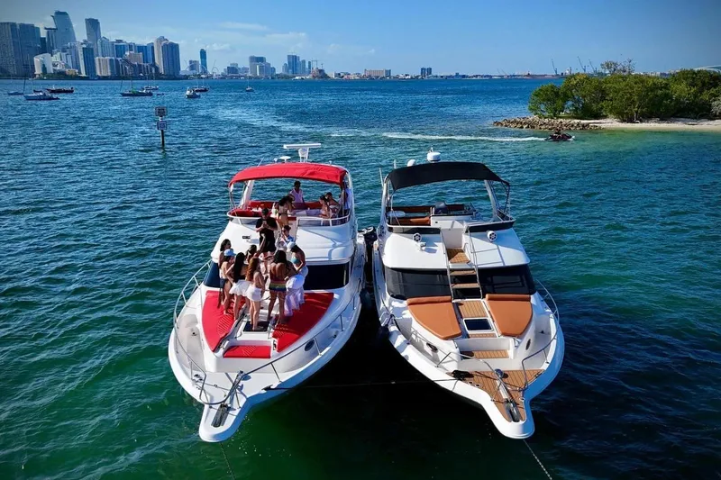 Slide: The Image of Two yachts anchored near a city skyline, featuring a 2002 Sea Ray 450 Express Bridge. - 12