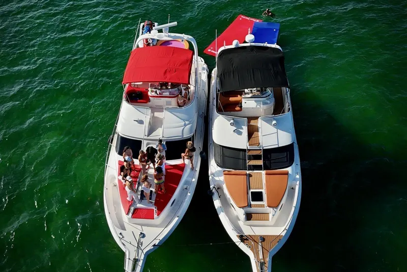 Slide: The Image of Two yachts, including a 2002 Sea Ray 450 Express Bridge, anchored with people enjoying the sun. - 15